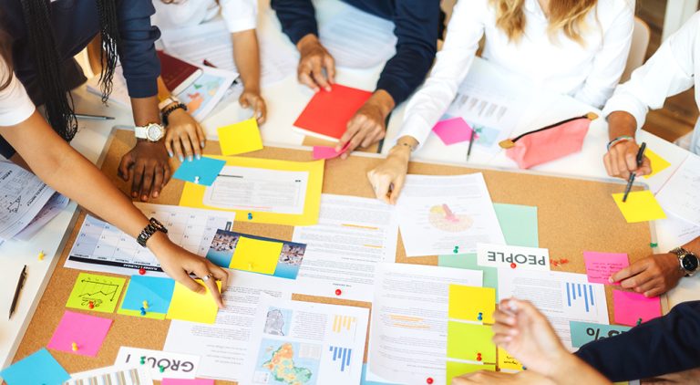 Young people engaged in policymaking activity with plans and paperwork laid out on a table