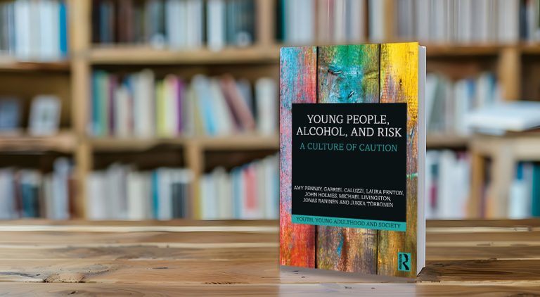 The book Young People, Alcohol, and Risk A Culture of Caution on a table with bookshelves behind