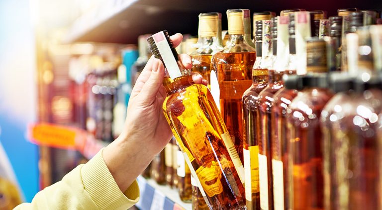 Person picking a bottle of alcohol off a shelf