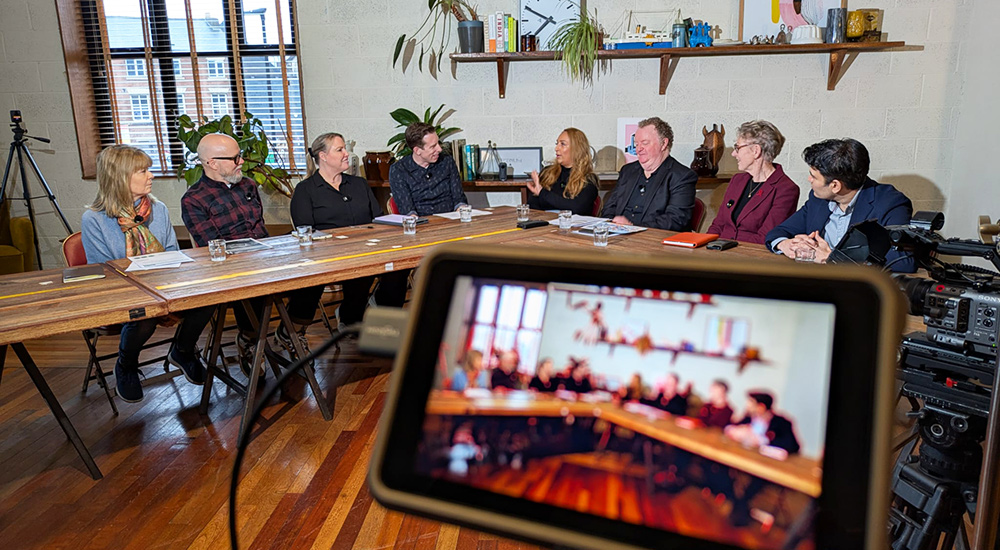 Close-up of a camera screen showing the alcohol policy roundtable panel members including Professor John Holmes, Aunee Bhogaita, Clive Henn, Dr Gautam Mehta, Rosanna O'Connor, Dr Peter Rice, Professor Julia Sinclair, and Alice Wiseman MBE.