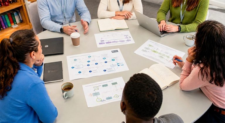 People sat around a table discussing documents about gambling modelling during a workshop
